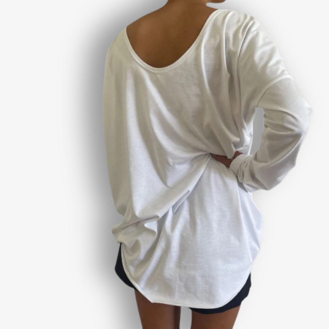 A person shown from the back wearing an oversized white long-sleeve top with a wide scoop neckline and a draped, loose fit, paired with black shorts against a plain white background.
