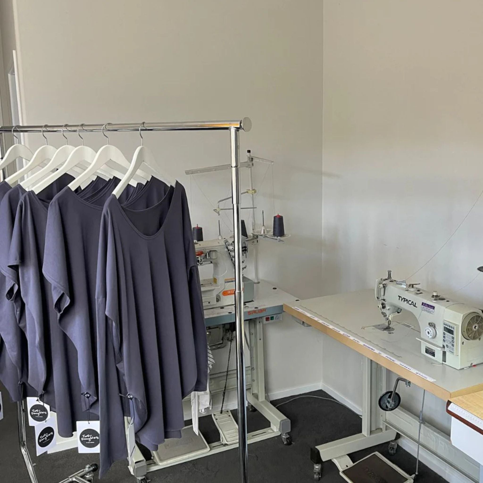 Clothing rack with shirts and a sewing machine in a workshop setting