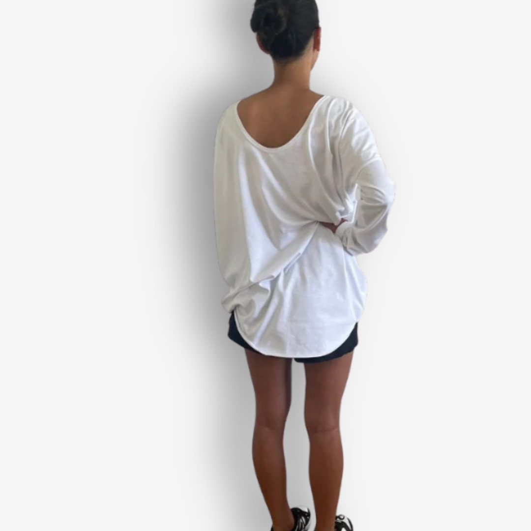 A woman viewed from behind wearing an oversized white long-sleeve top and black athletic shorts against a plain light gray background.